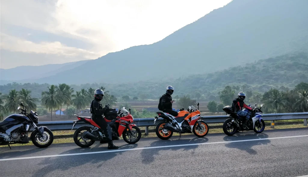 Grupo de motociclistas en carretera montañosa al amanecer, con motos deportivas y equipo completo de seguridad.