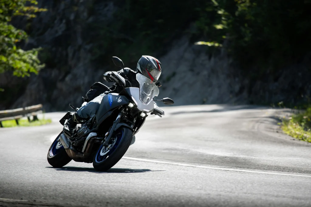 Motociclista curveando con precisión en carretera rural, usando casco y protecciones sobre moto deportiva touring Yamaha.