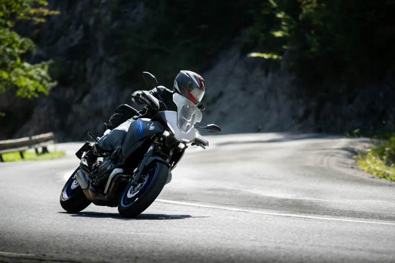 Motociclista curveando con precisión en carretera rural, usando casco y protecciones sobre moto deportiva touring Yamaha.
