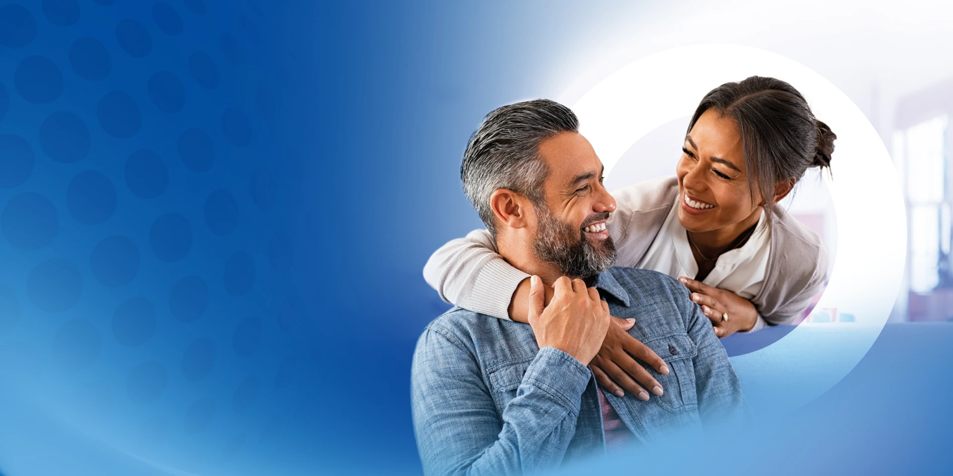 Pareja feliz se abraza y sonríe en casa, transmitiendo tranquilidad gracias a su seguro de vida.