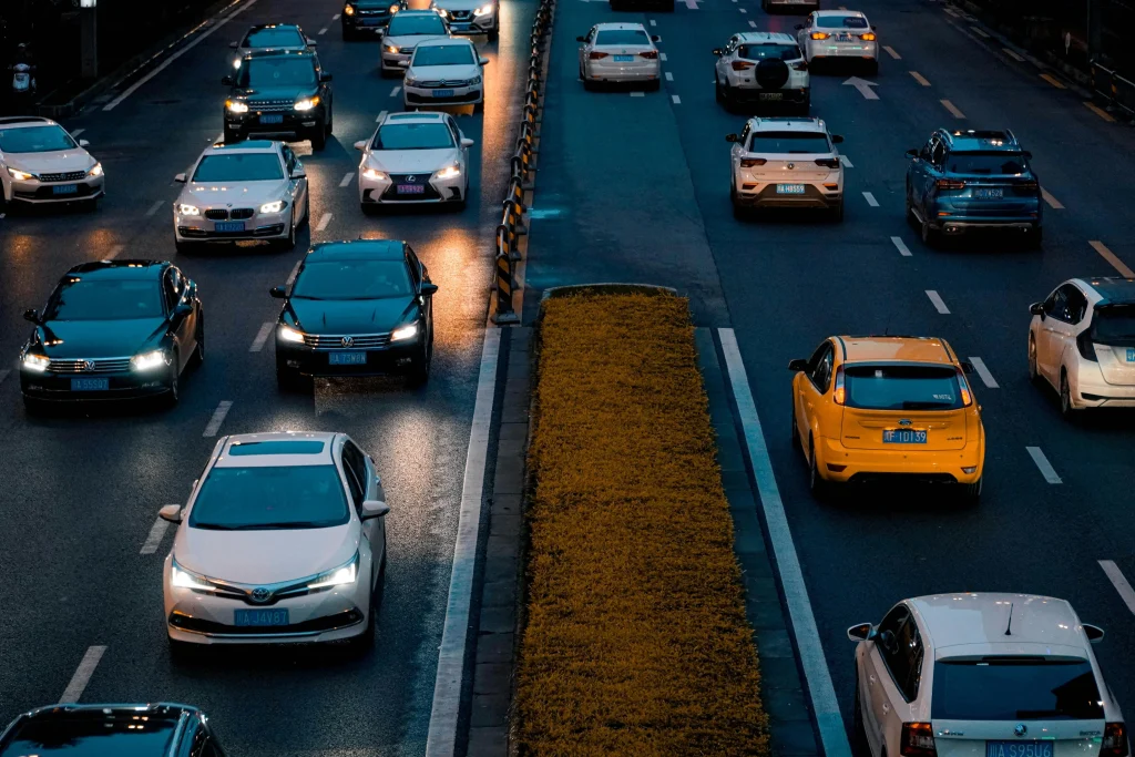 Tráfico intenso en carretera urbana por la noche con autos modernos, luces encendidas y carriles divididos.